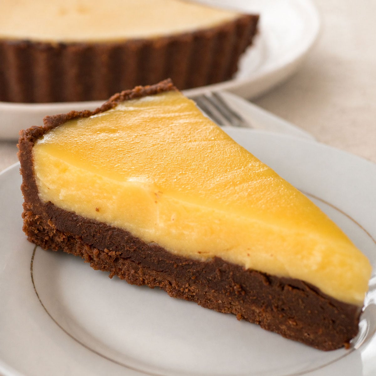 Slice of chocolate orange tart showing the chocolate crust, smooth ganache and creamy orange custard layers.