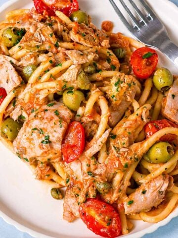 Close-up of tuna pasta with green olives, cherry tomatoes, capers, and chunky tuna