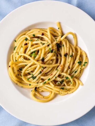 Anchovy pasta with spaghetti, parsley, red pepper flakes, and garlic on a white plate
