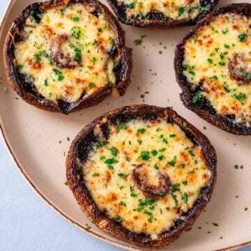 Close-up of cheesy baked portobello mushrooms with golden melted cheddar and parsley