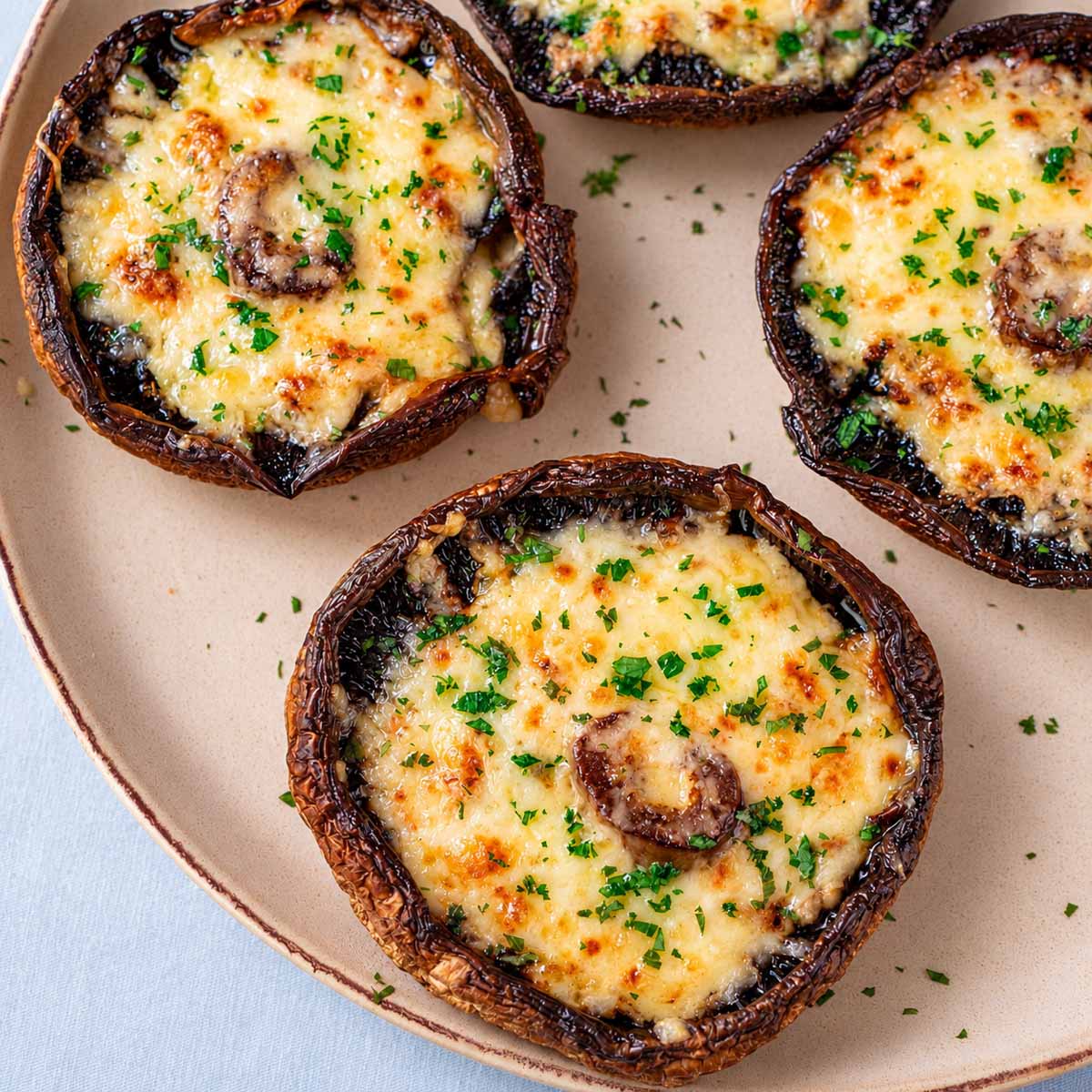 Close-up of cheesy baked portobello mushrooms with golden melted cheddar and parsley