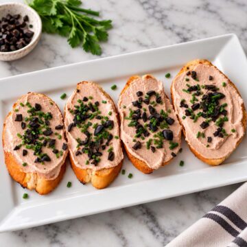 3 ingredient tuna dip with cream cheese served on toasted bread with chopped black olives and chives.