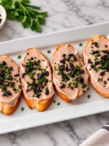 3 ingredient tuna dip with cream cheese served on toasted bread with chopped black olives and chives.