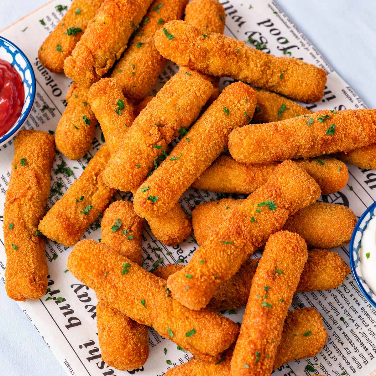 Golden breaded chicken fries piled on parchment with fresh parsley and dipping sauces