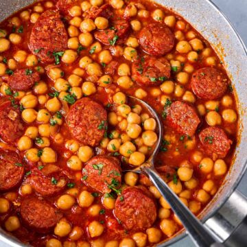 Close-up of chickpea and chorizo stew with sliced chorizo and tomato sauce