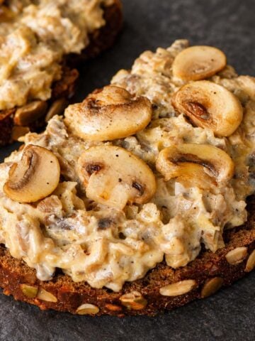 Seeded sourdough toast topped with creamy chopped mushrooms and golden sautéed mushroom slices.