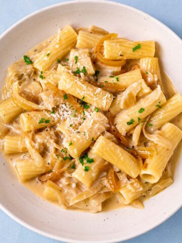Creamy rigatoni French onion pasta topped with Parmesan, parsley and caramelized onions