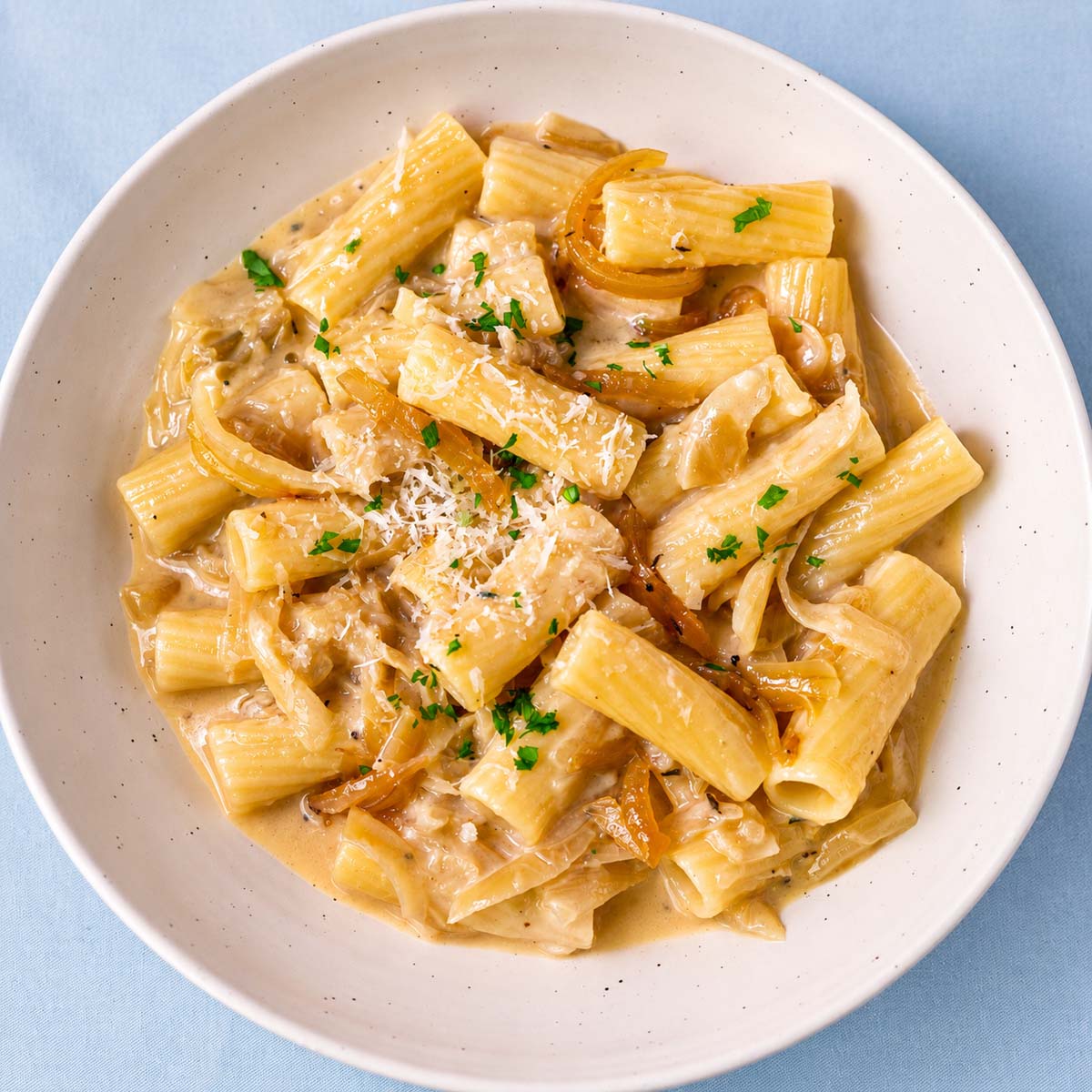 Creamy rigatoni French onion pasta topped with Parmesan, parsley and caramelized onions